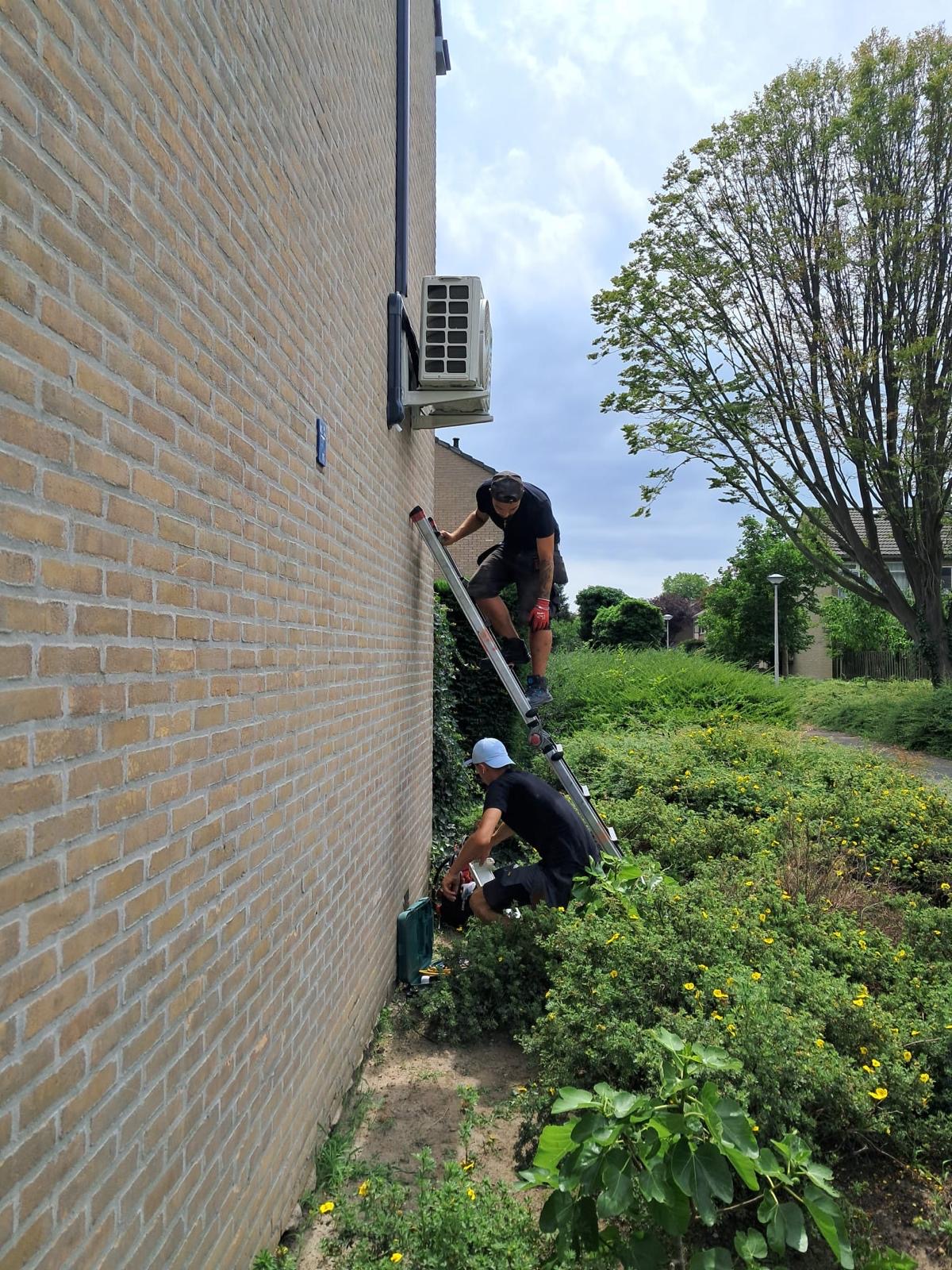 Monteurs van Airvolta plaatsen een airco buitenunit aan de gevel in Den Haag